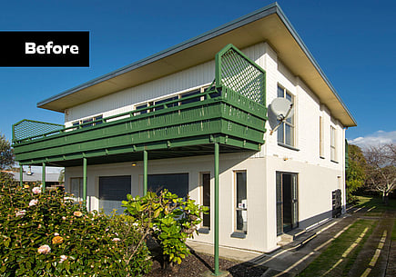 Home before the renovation build. An old and dated two-story 1970s home with mixed cladding and a green deck.