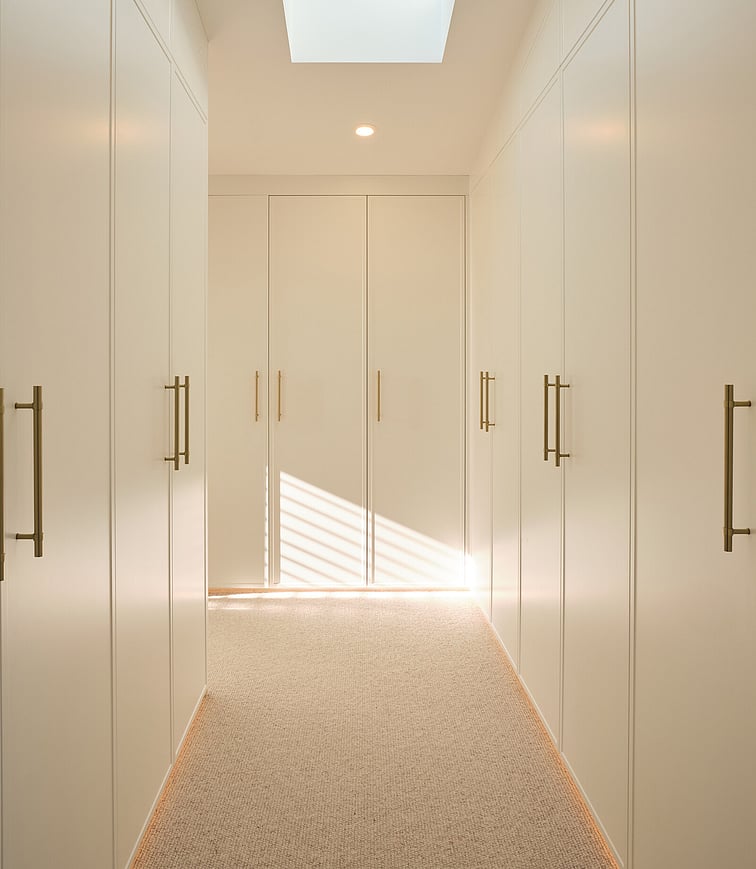 An outdoor garden setting showing the outdoor kitchen areas to the right and the corner of the deck on the left. Immaculate green lawn, raised garden, fence, and palm trees.