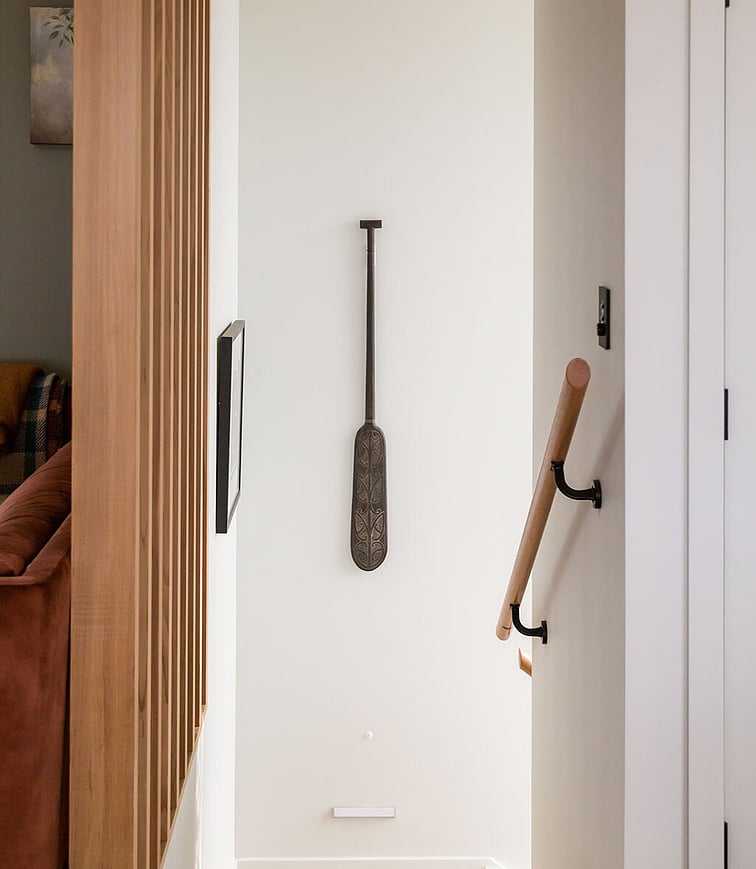 An outdoor garden setting showing the outdoor kitchen areas to the right and the corner of the deck on the left. Immaculate green lawn, raised garden, fence, and palm trees.