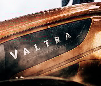 Close-up of the Valtra logo on the metallic bronze bodywork of the S Series tractor, detailed with raindrops and a sleek finish.