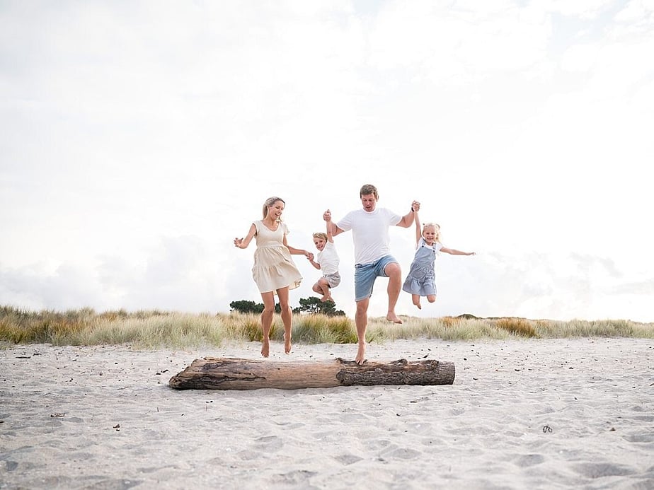 Tauranga Photographer.  Family on the beach jumping off a log.  Jackie O'Photography.  Papamoa Family Photographer.