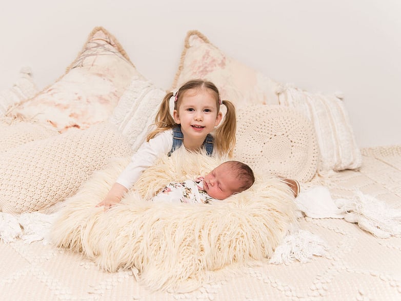 girl looking at the camera with her newborn baby sister