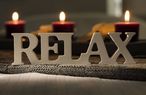 Picture of a Relax Sign on a table with red candles light behind