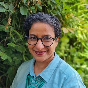 Photo of woman with mid length black hair standing in front of brick wall