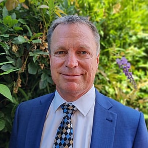 Photo of man with short brown hair in front of brick wall