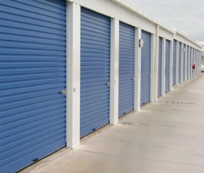 cream residential garage door with white trimming, and light grey weatherboard