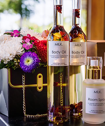 A small flower arrangement with body oil in tall glass bottles.