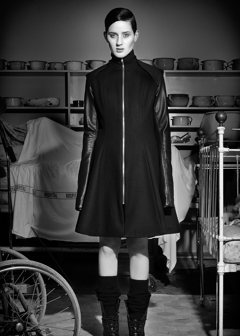 A model wearing a black zip up coat designed by Jane Sutherland. Photographed at Demolition World in Southland.