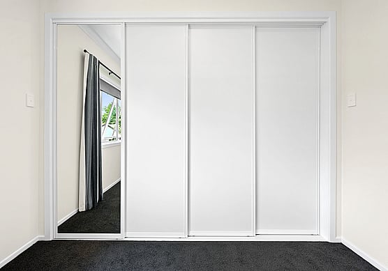 A white fitted wardrobe with sliding door.