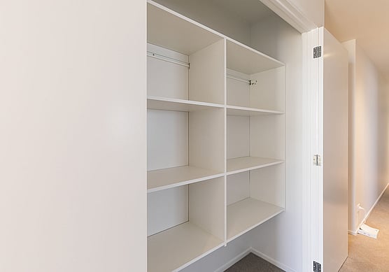 Hallway cupboard with white shelving and doors.