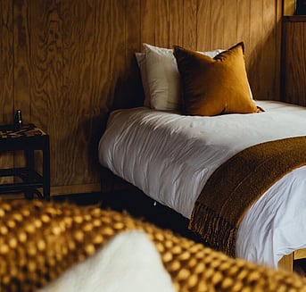 Made up single bed in a whare