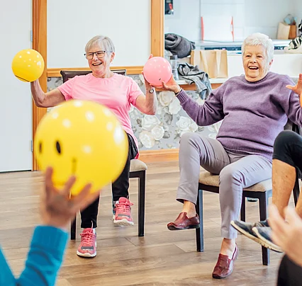 Older women sitting on chairs doing excercise