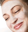 An image of a lady smiling with her eyes shut and face peel cream on her face during a Ultraceutical peel treatment
