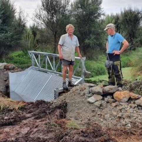 Landowner Theo Bongers (right) and consultant John Gumbley (left) inspect the newly installed koi carp barrier at the outlet of Lake Ruatuna. (Living Water)