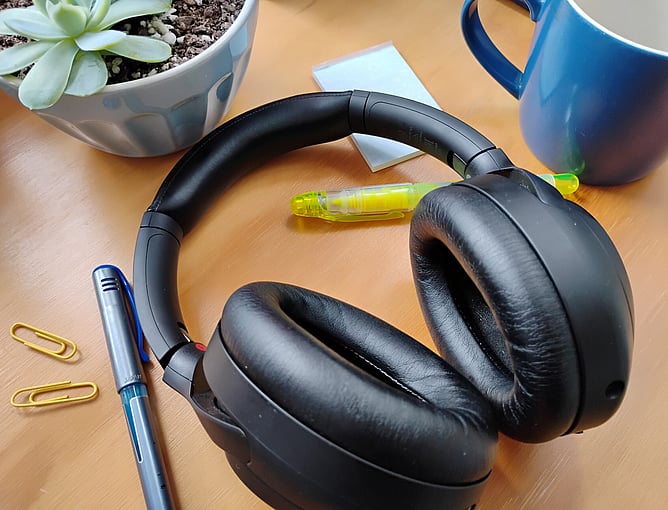 Headphones on a desk surrounded by stationery items and other necessities
